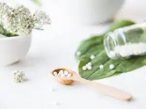 homeopathic granules, medicinal herbs on a natural wooden table