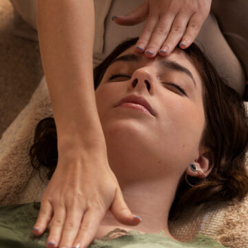 Femme allongée sur le dos, les bras étendus, sur un fond neutre.