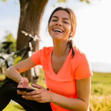 Une femme assise sur l'herbe, utilisant son téléphone portable.